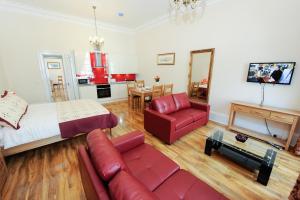 a living room with a bed and a red couch at Edinburgh City Suites in Edinburgh