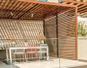 a patio with a table and chairs and a wooden pergola at Skiathos Symbol Villas in Achladies