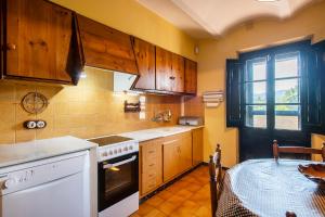 a kitchen with wooden cabinets and a table in it at Casa rural ideal para familias y amigos in Serinyà