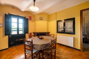 a dining room with a table and chairs and a clock at Casa rural ideal para familias y amigos in Serinyà