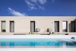 a house with a swimming pool in front of it at Skiathos Symbol Villas in Achladies