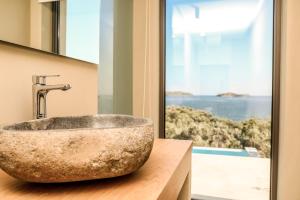 a bathroom with a stone sink and a window at Skiathos Symbol Villas in Achladies