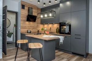 a kitchen with gray cabinets and a counter with stools at Loftowy Zakątek in Leszno