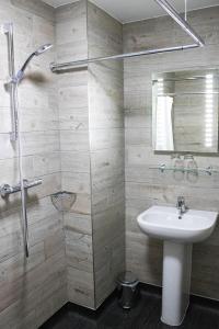 a bathroom with a sink and a shower with a mirror at Belmont Llandudno in Llandudno