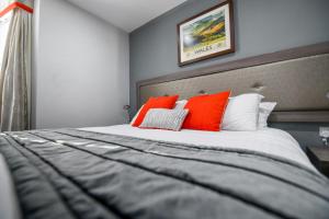 a bedroom with a large bed with orange pillows at Belmont Llandudno in Llandudno