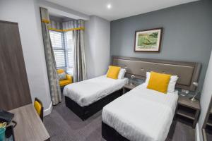 a hotel room with two beds with yellow pillows at Belmont Llandudno in Llandudno