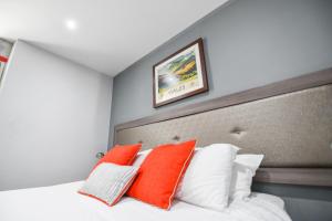 a bedroom with a bed with orange and white pillows at Belmont Llandudno in Llandudno