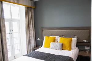a bedroom with a bed with yellow pillows and a window at Belmont Llandudno in Llandudno