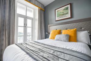 a bedroom with a bed with yellow pillows and a window at Belmont Llandudno in Llandudno