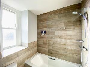 a bathroom with a tub and a toilet and a window at Belmont Llandudno in Llandudno