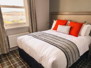 a bedroom with a bed with orange pillows and a window at Belmont Llandudno in Llandudno