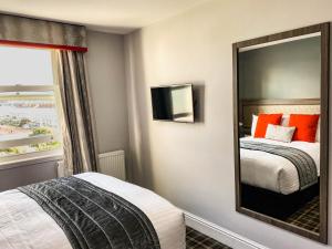 a bedroom with a mirror and a bed and a window at Belmont Llandudno in Llandudno