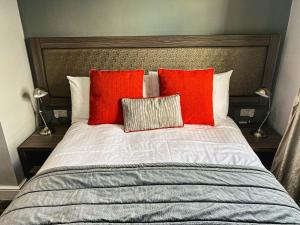 a bed with two red pillows on top of it at Belmont Llandudno in Llandudno