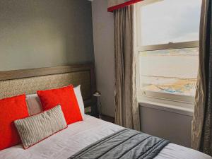 a bedroom with a bed with red pillows and a window at Belmont Llandudno in Llandudno