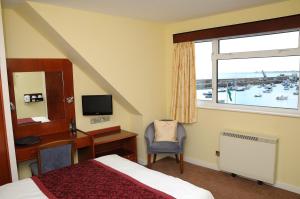 Cette chambre comprend un lit, un bureau et une fenêtre. dans l'établissement Dolphin Hotel, à Gorey