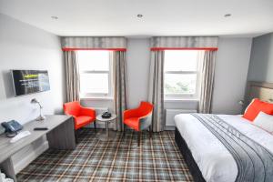 a hotel room with a bed and two red chairs at Belmont Llandudno in Llandudno