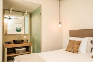 a bedroom with a bed with a mirror and a sink at Skiathos Symbol Villas in Achladies