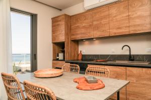 a kitchen with wooden cabinets and a table with chairs at Skiathos Symbol Villas in Achladies