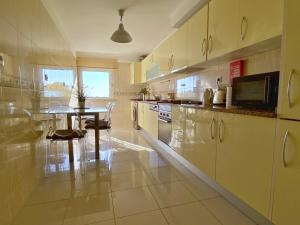 a kitchen with white cabinets and a table in it at Jardins da Parede 211 in Parede