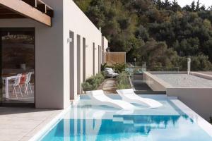 a swimming pool with white chairs next to a building at Skiathos Symbol Villas in Achladies
