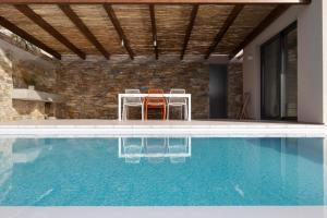 a house with a swimming pool with two chairs and a table at Skiathos Symbol Villas in Achladies