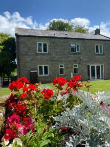 a house with red flowers in front of it at Delightful stone barn, with superb views, Ramsgill in Pateley Bridge