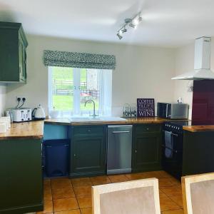 a kitchen with green cabinets and a sink and a window at Delightful stone barn, with superb views, Ramsgill in Pateley Bridge