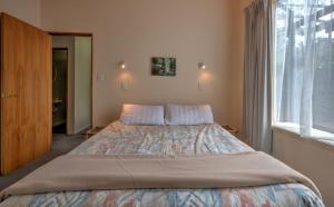 a bed in a bedroom with a large window at 34 Denby Place in Hanmer Springs