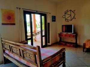 Habitación con cama, TV y puerta en Chale Por do Sol, en Ilhabela