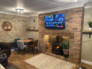 uma sala de estar com lareira e uma televisão numa parede de tijolos em The Wynd Cottage em Amble