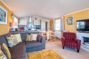sala de estar con sofá y TV y cocina en Chelsea Lodge - Aldeburgh Coastal Cottages, en Sizewell