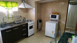 a kitchen with a sink and a stove and a microwave at Perlas del Mar in Puerto Madryn