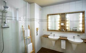 ein Badezimmer mit zwei Waschbecken und einem Spiegel und einer Dusche in der Unterkunft Hotel Mardaga in As