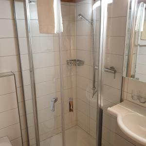 una ducha con una puerta de cristal junto a un lavabo en WHITE HOME IN AESCHI BEI SPIEZ en Aeschi bei Spiez