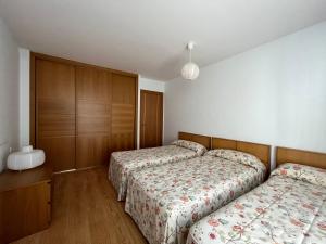 a bedroom with two beds and wooden cabinets at Casa Damián del Baile Apartamentos in Benasque