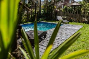 a pool with a wooden deck and two benches at Costa Palmera a 295 m de playa in Mar Azul