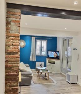 een woonkamer met een bank en een tv bij Logis Sainte Claire in Montauban