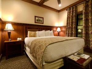 The Lodge at Cloudcroft في كلاودكروفت: غرفة نوم بسرير كبير وطاولتين مع مصابيح