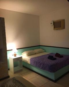 a bedroom with a bed and a table with a lamp at Casa Vermelha Búzios in Búzios
