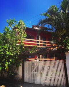 une maison rouge avec une porte blanche et des arbres dans l'établissement Casa Vermelha Búzios, à Búzios