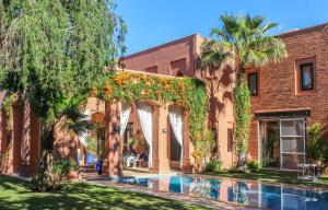 a house with a swimming pool in front of a building at Magnificent Villa "Golf Amelkis" in Marrakesh