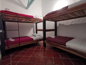 two bunk beds in a room with a red tile floor at Hostel Once Once in Villa de Leyva