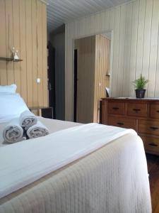 ein Schlafzimmer mit einem weißen Bett und einer Holzkommode in der Unterkunft Happy House - Casa ideal para grupos na cidade dos Canyons in Praia Grande