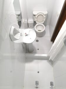 a white toilet sitting in a bathroom next to a sink at Amakonkay Machupicchu in Machu Picchu