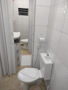Baño blanco con aseo y lavamanos en O Portuga Pousada, en João Pessoa
