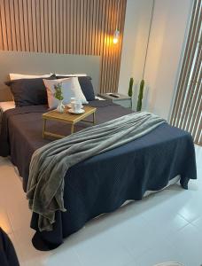 a bed with a blue blanket and a table at Loft completo e refinado in Ribeirão Preto