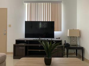 a living room with a flat screen tv on a entertainment center at Joe's Place- Private 3 Bedroom Apartment in Flora Pago Gardens