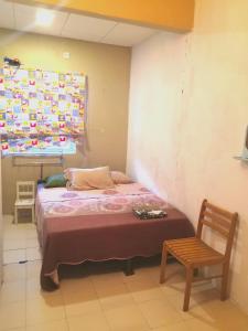 1 dormitorio pequeño con 1 cama y 1 silla en Sutera Damai Homestay, en Kampong Belah Dua