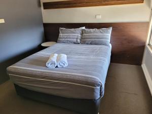 uma cama com dois pares de chinelos em Palm and Pawn Motor Inn em North Wagga