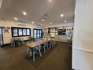 a cafeteria with tables and chairs and a kitchen at Palm and Pawn Motor Inn in North Wagga